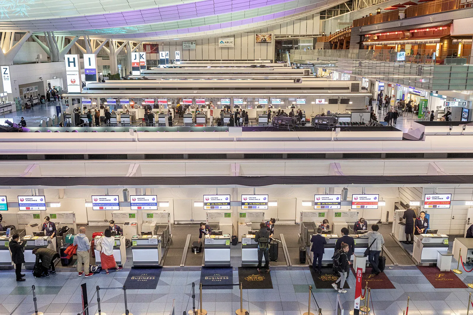 Wide airport check-in hall with rows of counters and travellers in Japan