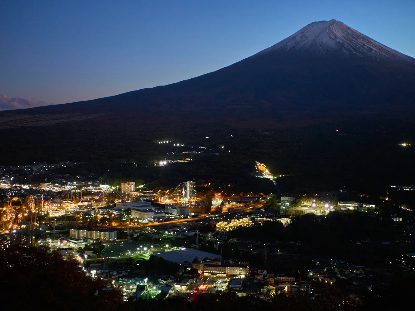 Mount Fuji silhouette at dusk above glowing town lights